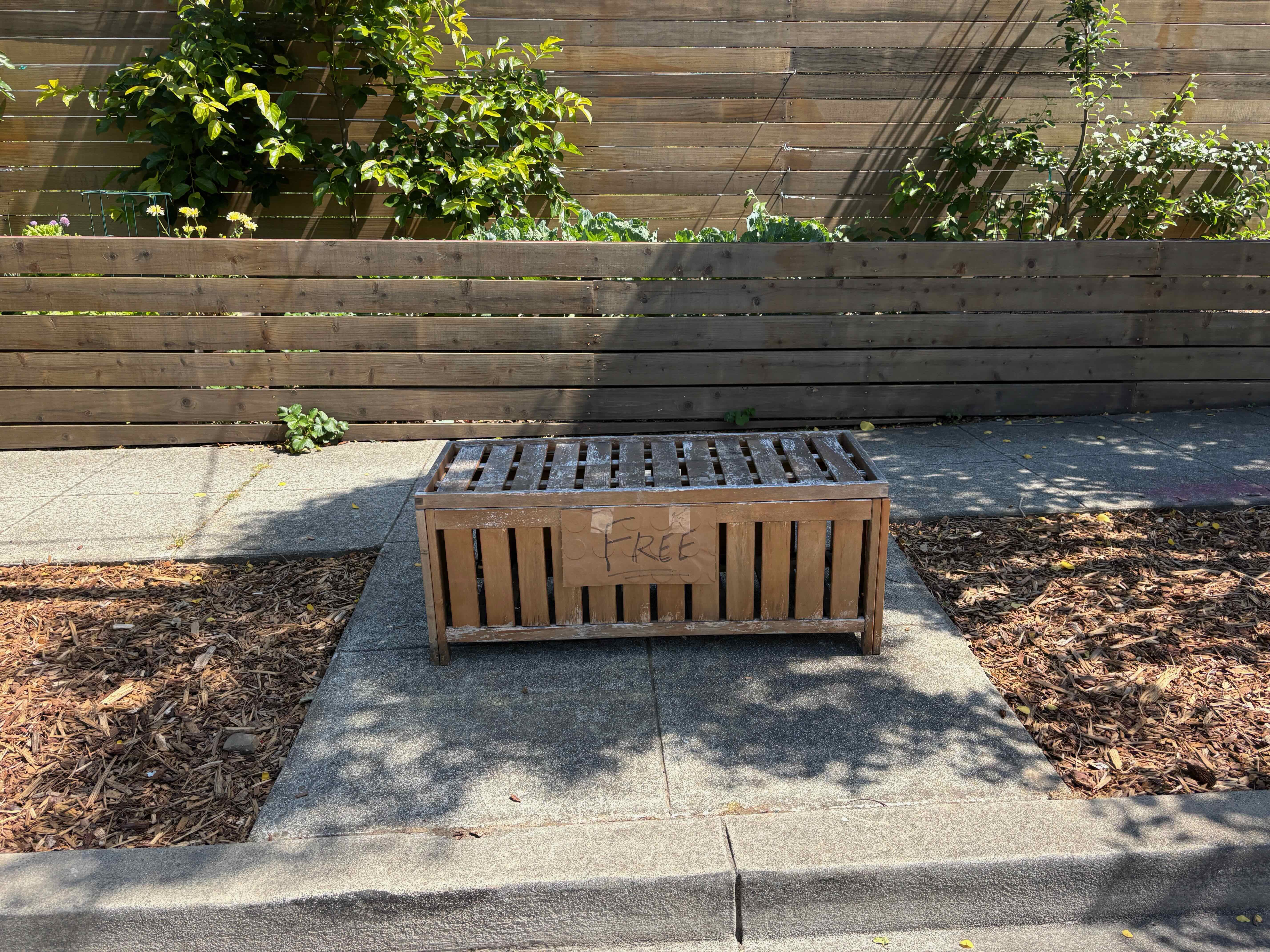 Wooden outdoor bench on a sidewalk with a FREE sign