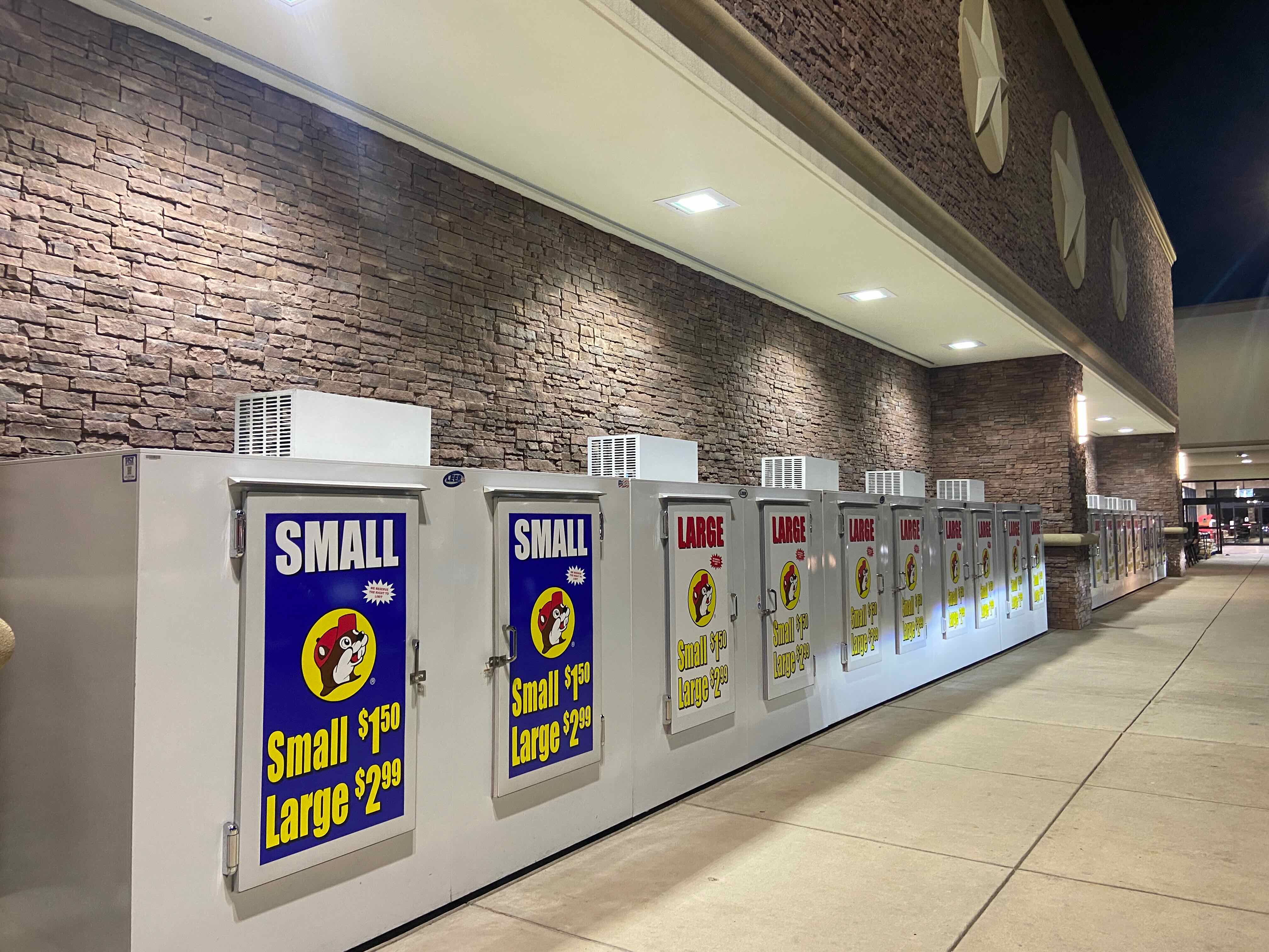 PHOTO: Ice machine wall, exterior night — a dozen branded machines running the length of the facade
