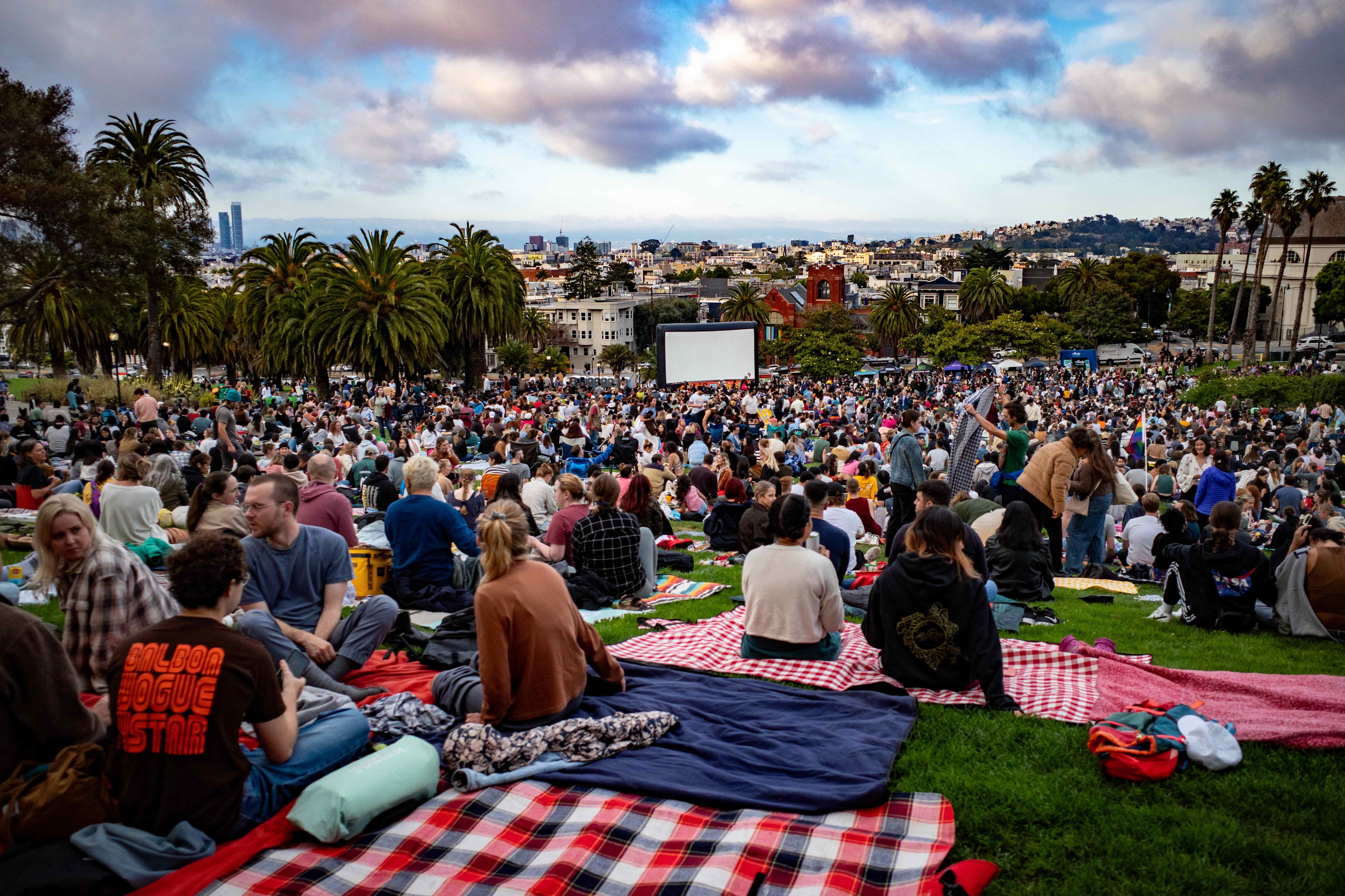 People gathered on the lawn at Dolores Park, San Francisco, with the city skyline in the background