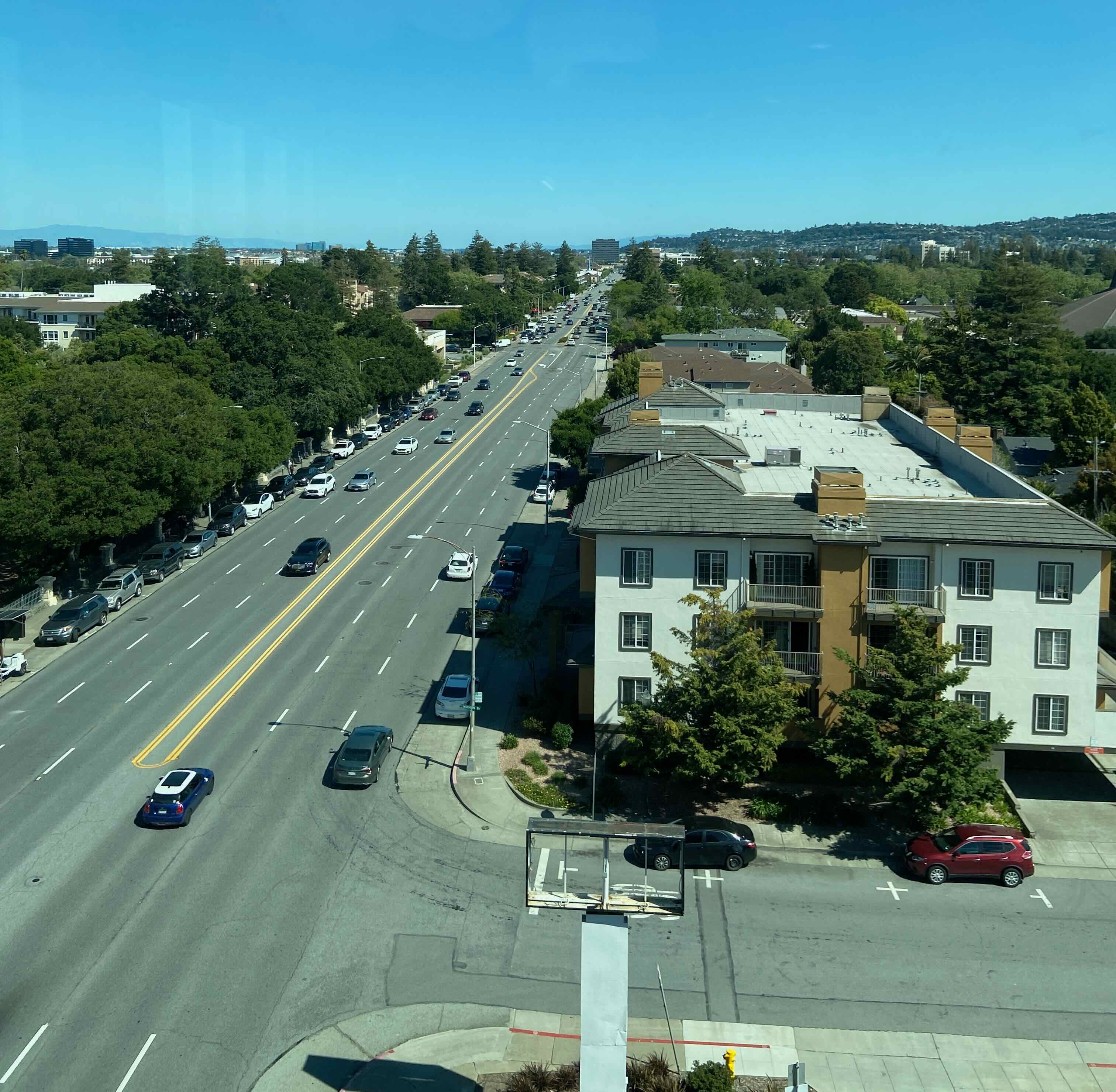 Aerial view of El Camino Real stroad in San Mateo, a wide multi-lane arterial road with low-density buildings and a bus stop with no shelter