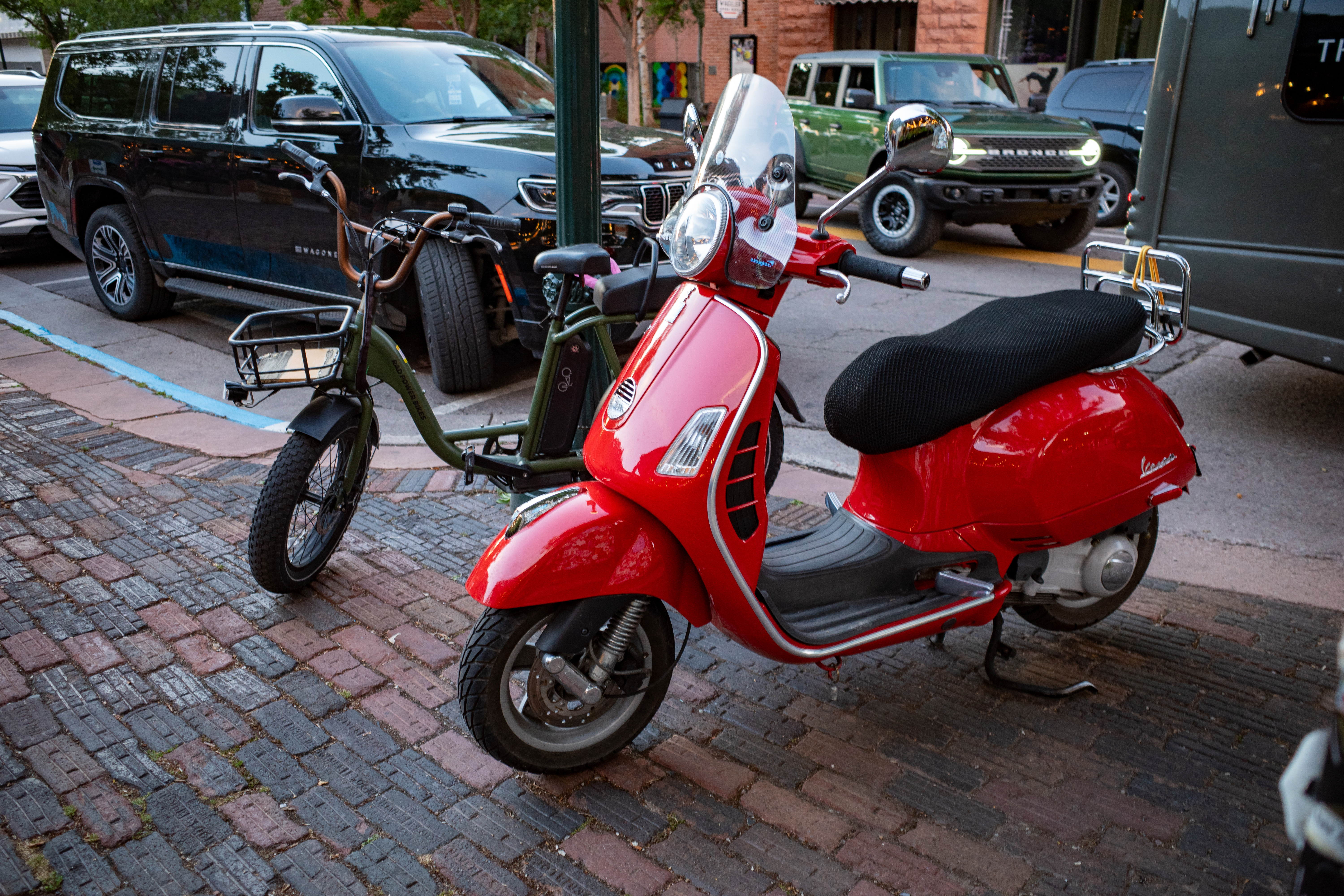 a Vespa in the foreground before a Rad e-bike, with cars filling out the background