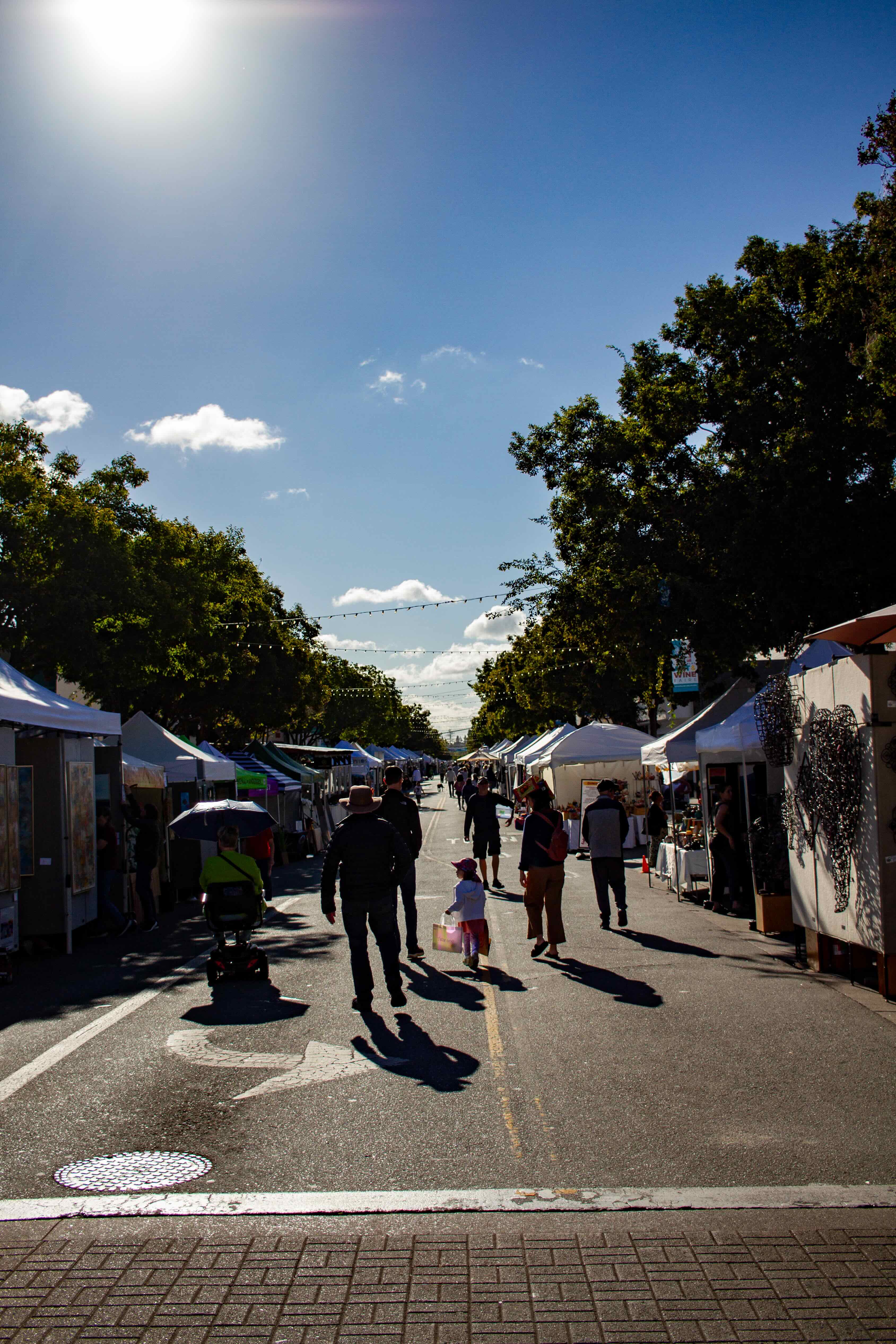 A sunny craft festival on Laurel Street in San Carlos with vendor stalls lining both sides of the street