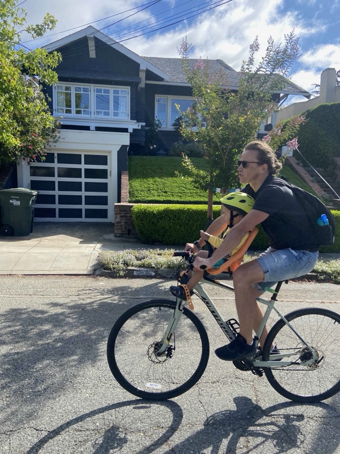 A child in a front-mounted seat between the rider's arms on a bicycle