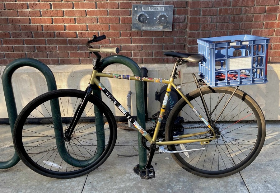 A milk crate zip-tied to a rear rack, filled with groceries